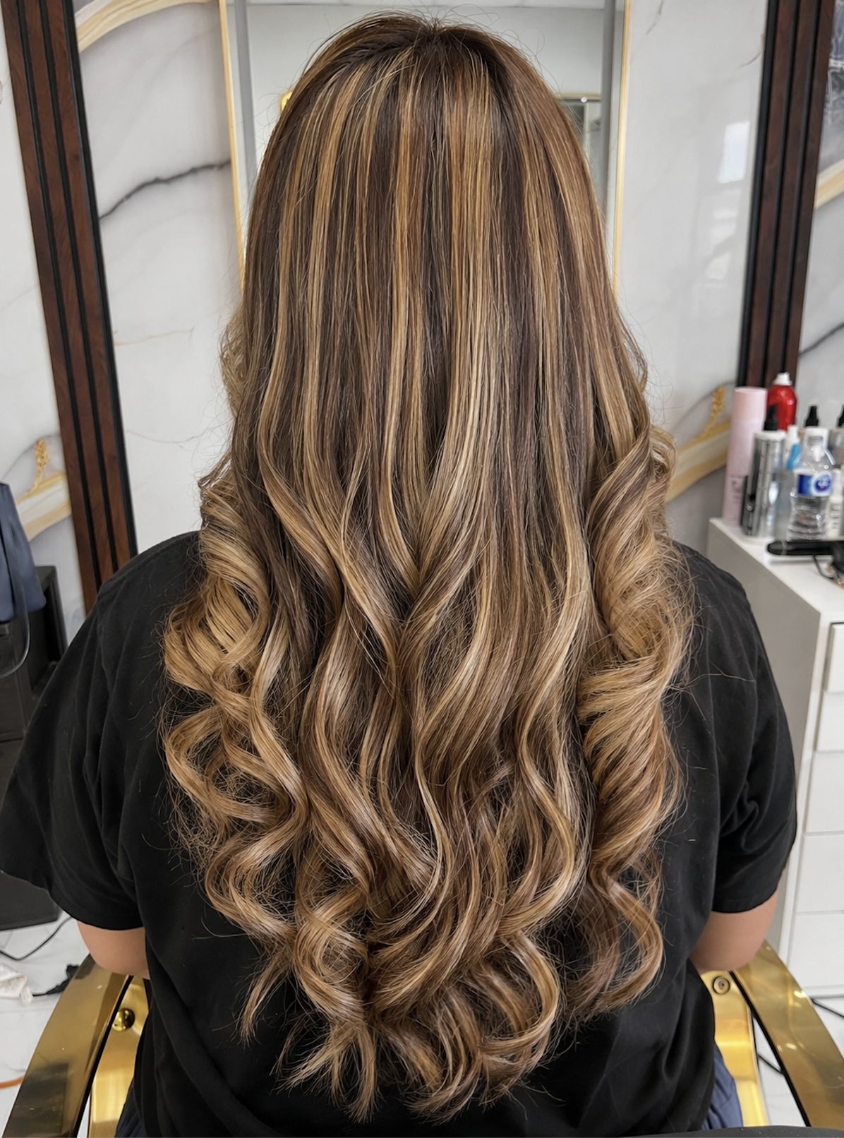 Caramel balayage highlights with soft waves by a Surrey hairstylist